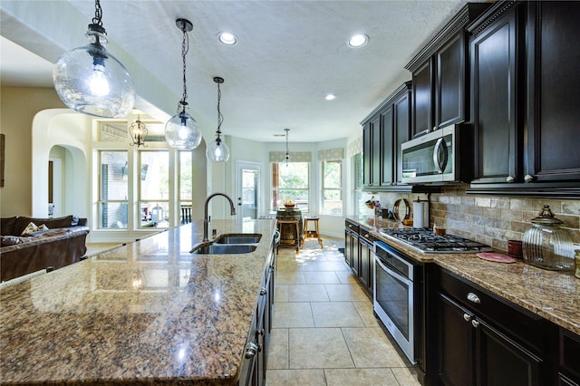 7003 Fall Creek Ln, Missouri City, TX 77459 - kitchen featuring stainless steel appliances, a large island with sink, dark stone counters, recessed lighting, and tasteful backsplash