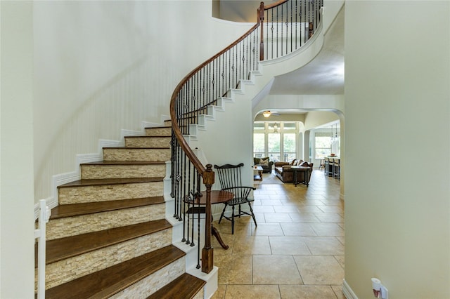 7003 Fall Creek Ln, Missouri City, TX 77459 - staircase featuring arched walkways, a towering ceiling, and tile patterned flooring