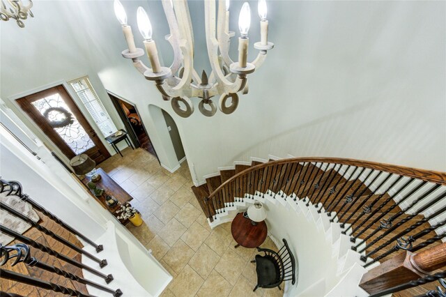 7003 Fall Creek Ln, Missouri City, TX 77459 - staircase featuring arched walkways, stone finish floors, a towering ceiling, and a chandelier