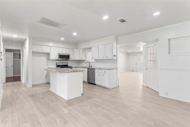 10906 Keese Dr, Houston, TX 77089 - kitchen with stainless steel appliances, white cabinets, a kitchen island, recessed lighting, and light wood-type flooring