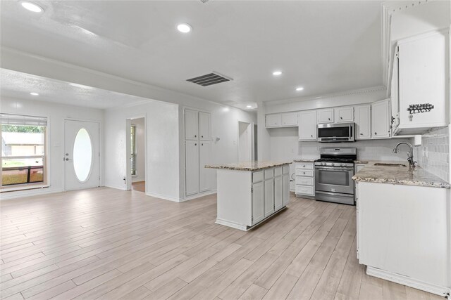 10906 Keese Dr, Houston, TX 77089 - kitchen with stainless steel appliances, light wood-style floors, light stone countertops, a kitchen island, and recessed lighting