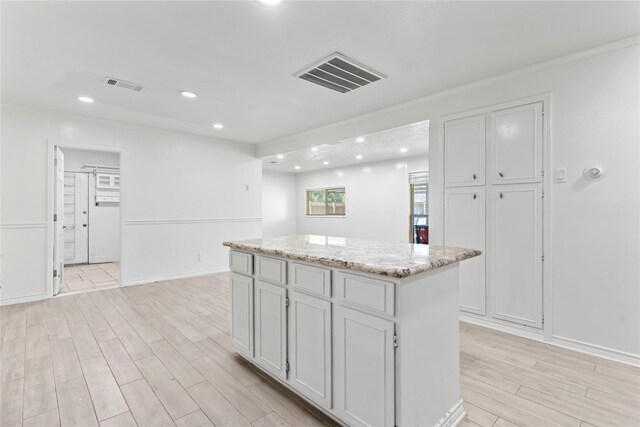 10906 Keese Dr, Houston, TX 77089 - kitchen featuring light wood-style flooring, recessed lighting, a center island, light stone countertops, and white cabinetry