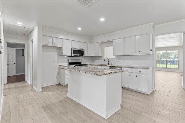 10906 Keese Dr, Houston, TX 77089 - kitchen with stainless steel appliances, white cabinetry, light wood finished floors, a kitchen island, and ornamental molding