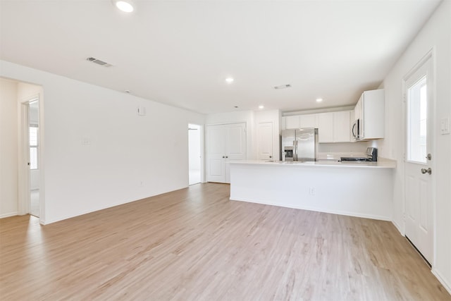 17427 Cyprian Cedar Ln, New Caney, TX 77357 - kitchen featuring stainless steel fridge, range, a peninsula, light wood-type flooring, and light countertops