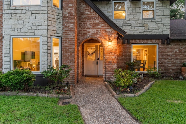 24111 Norchester Way, Spring, TX 77389 - view of exterior entry featuring brick siding, a shingled roof, and a yard