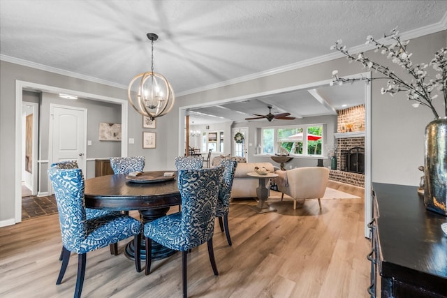 24111 Norchester Way, Spring, TX 77389 - dining area featuring light wood-type flooring, a chandelier, a brick fireplace, ornamental molding, and a ceiling fan