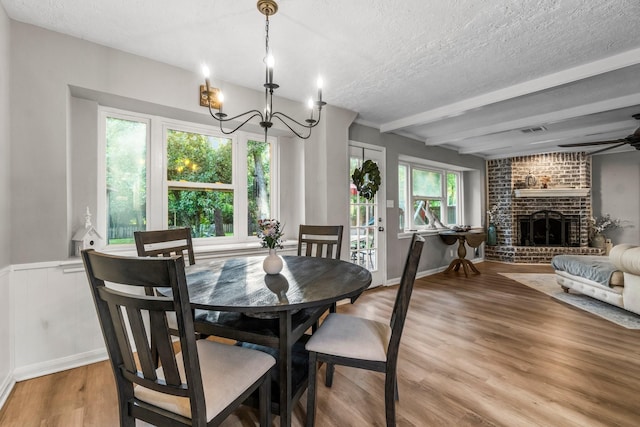 24111 Norchester Way, Spring, TX 77389 - dining space with a chandelier, light wood-style flooring, a textured ceiling, a fireplace, and a ceiling fan