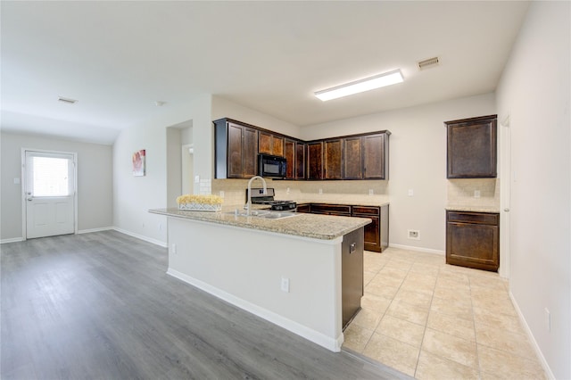 9207 Ranch Ridge Ln, Richmond, TX 77407 - kitchen featuring black microwave, decorative backsplash, dark brown cabinetry, a peninsula, and stainless steel gas range oven