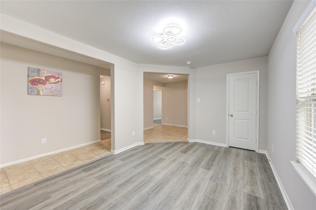 9207 Ranch Ridge Ln, Richmond, TX 77407 - empty room featuring light wood finished floors, plenty of natural light, and a textured ceiling