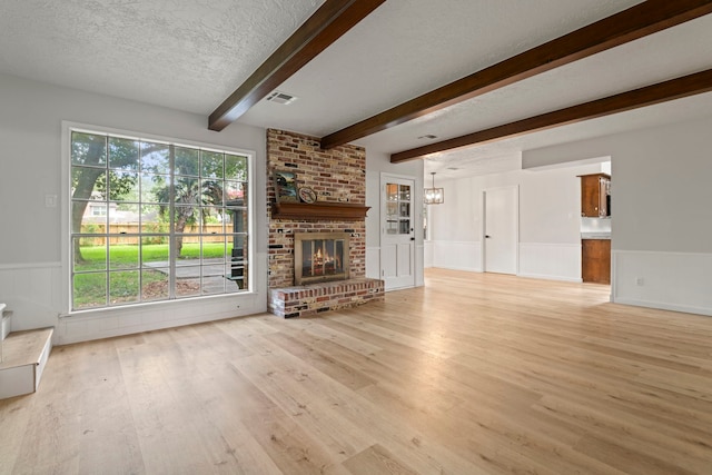 6515 Pebble Beach Dr, Houston, TX 77069 - unfurnished living room featuring wainscoting, light wood-type flooring, beam ceiling, a textured ceiling, and a brick fireplace