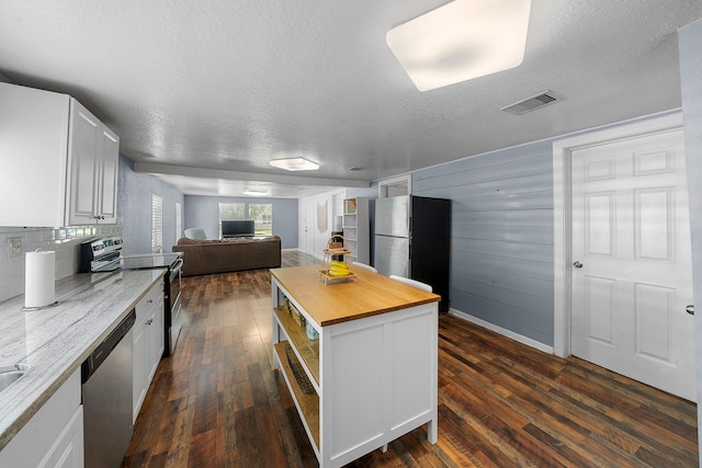 1305 Fairview Dr, Alvin, TX 77511 - kitchen featuring stainless steel appliances, wooden counters, open floor plan, dark wood-style flooring, and a textured ceiling