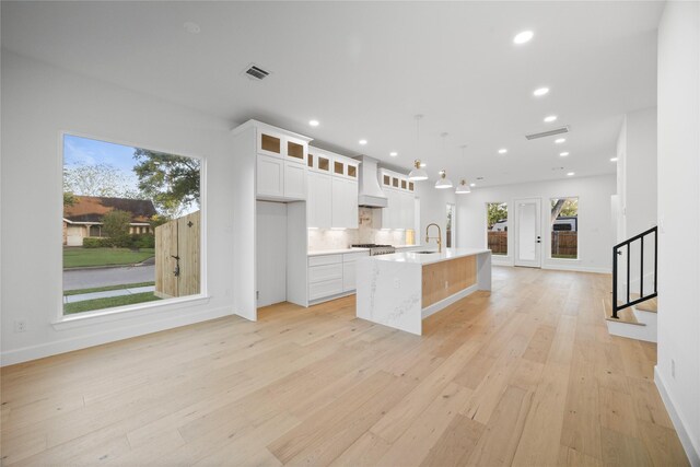 8646 Alcott Dr, Houston, TX 77080 - kitchen featuring custom range hood, light wood-type flooring, an island with sink, light countertops, and recessed lighting