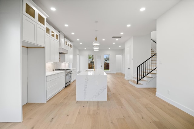 8646 Alcott Dr, Houston, TX 77080 - kitchen featuring stainless steel range, custom range hood, recessed lighting, light wood-type flooring, and tasteful backsplash