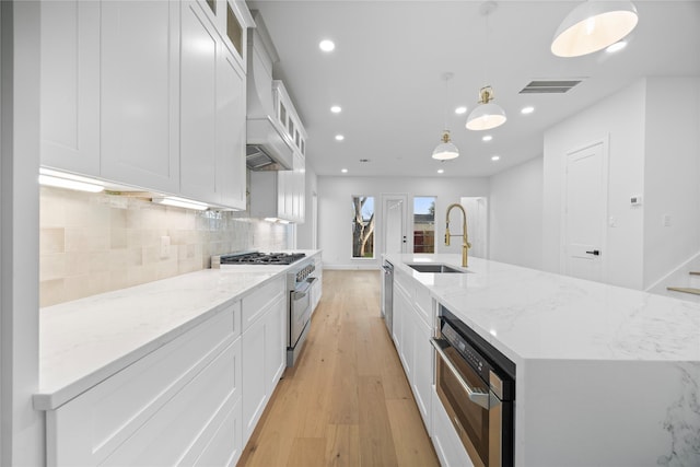 8646 Alcott Dr, Houston, TX 77080 - kitchen with stainless steel appliances, light wood finished floors, white cabinets, backsplash, and a large island
