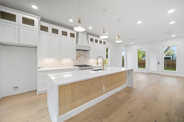 8646 Alcott Dr, Houston, TX 77080 - kitchen featuring premium range hood, light wood finished floors, tasteful backsplash, an island with sink, and recessed lighting