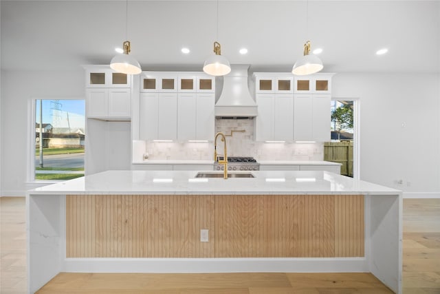 8646 Alcott Dr, Houston, TX 77080 - kitchen with custom range hood, a spacious island, tasteful backsplash, light wood finished floors, and light stone countertops