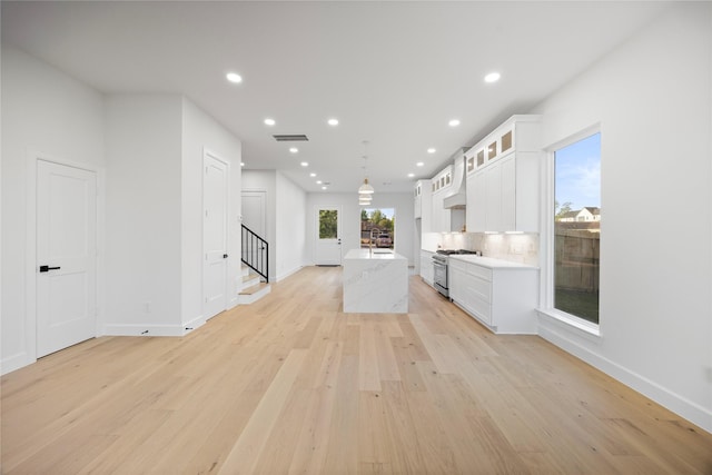 8646 Alcott Dr, Houston, TX 77080 - kitchen with stainless steel range, light wood-style floors, a kitchen island with sink, white cabinetry, and recessed lighting