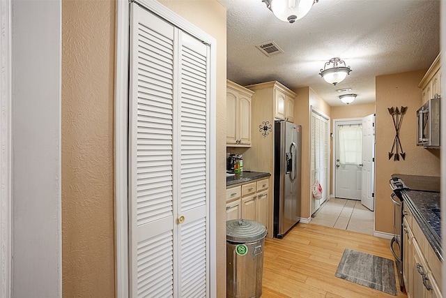 541 N Village Creek Pkwy, Lumberton, TX 77657 - kitchen with appliances with stainless steel finishes, dark countertops, light wood-type flooring, a textured ceiling, and cream cabinetry