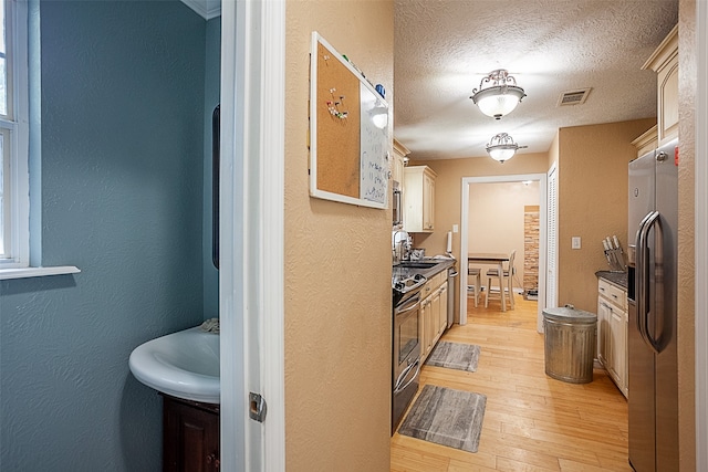 541 N Village Creek Pkwy, Lumberton, TX 77657 - kitchen with appliances with stainless steel finishes, light wood-type flooring, a textured wall, and a textured ceiling