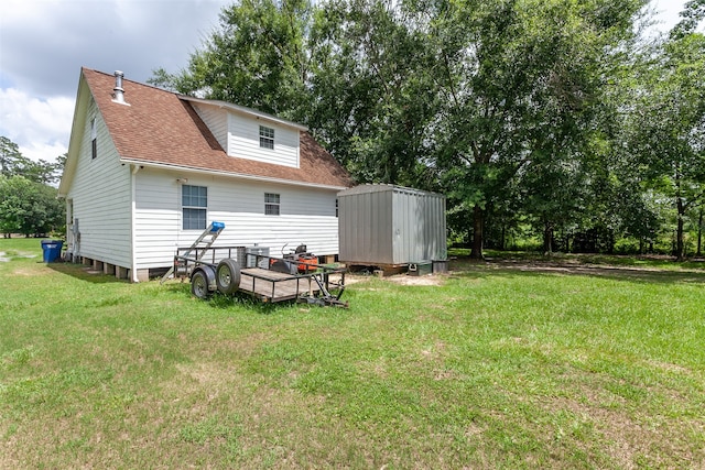 541 N Village Creek Pkwy, Lumberton, TX 77657 - back of property featuring a storage unit, roof with shingles, and a yard