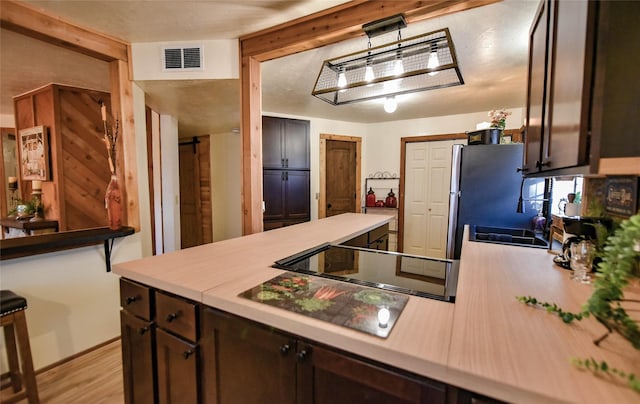 507 W Fawn St, Caldwell, TX 77836 - kitchen featuring dark brown cabinetry, light countertops, black electric cooktop, and light wood-type flooring