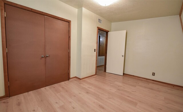 507 W Fawn St, Caldwell, TX 77836 - unfurnished bedroom featuring light wood finished floors, a closet, and a textured ceiling