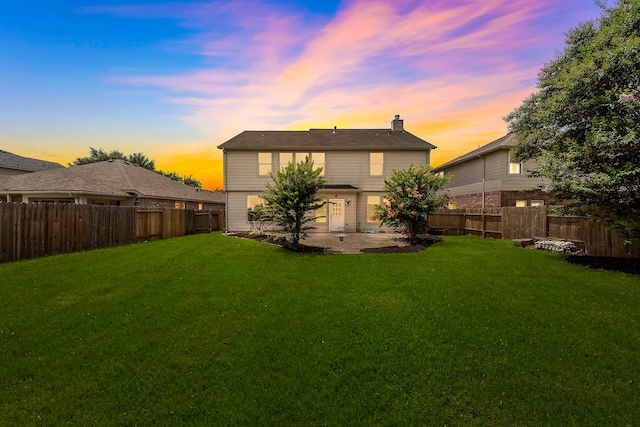 6306 Channelbrook Ln, Spring, TX 77379 - back of house at dusk with a fenced backyard, a chimney, and a patio area
