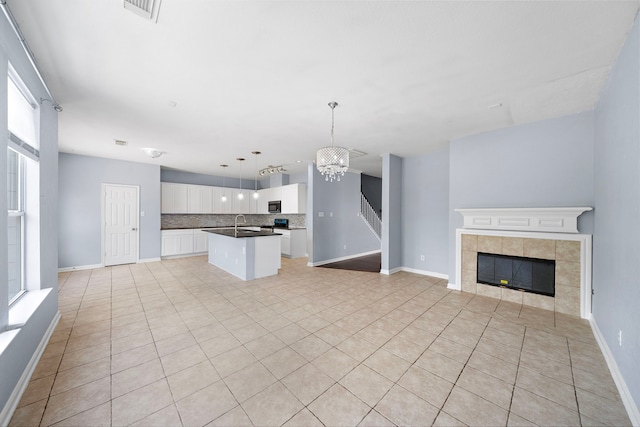 6306 Channelbrook Ln, Spring, TX 77379 - kitchen featuring open floor plan, a center island with sink, stainless steel microwave, and backsplash