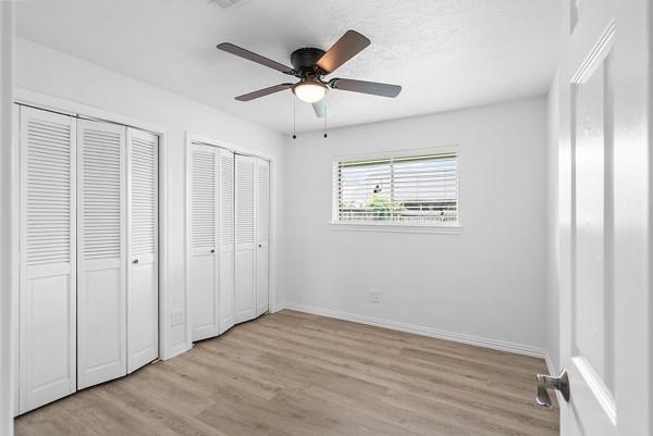 14419 Crosshaven Dr, Houston, TX 77015 - unfurnished bedroom featuring multiple closets, light wood-type flooring, and a ceiling fan
