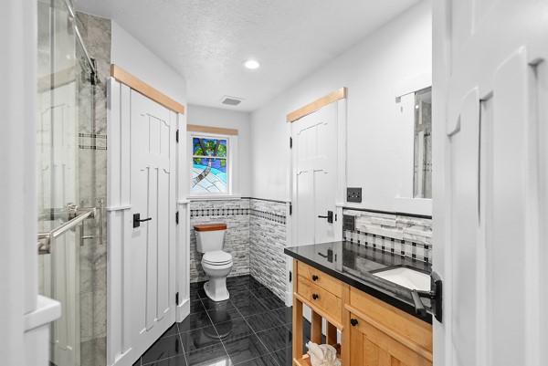 14419 Crosshaven Dr, Houston, TX 77015 - full bath with tile walls, a stall shower, tile patterned floors, vanity, and wainscoting