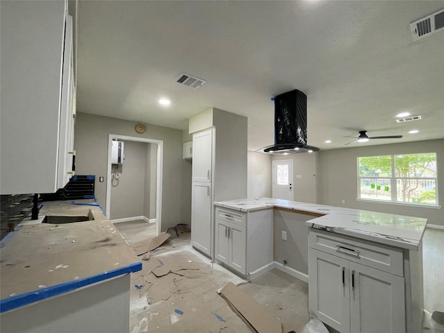 5039 Briscoe St, Houston, TX 77033 - kitchen with light stone counters, a peninsula, white cabinetry, extractor fan, and a ceiling fan
