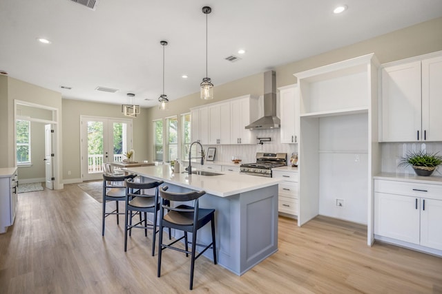4101 E Rogers St, Houston, TX 77022 - kitchen with wall chimney exhaust hood, stainless steel stove, backsplash, white cabinets, and recessed lighting