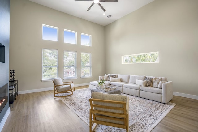 4101 E Rogers St, Houston, TX 77022 - living area with a high ceiling, a ceiling fan, a glass covered fireplace, and light wood finished floors