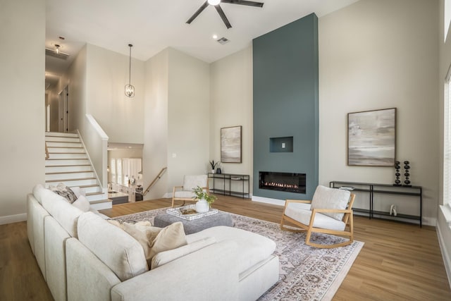 4101 E Rogers St, Houston, TX 77022 - living area featuring a towering ceiling, ceiling fan, stairs, wood finished floors, and a glass covered fireplace