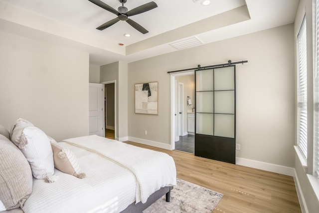 4101 E Rogers St, Houston, TX 77022 - bedroom featuring a barn door, a raised ceiling, wood finished floors, multiple windows, and recessed lighting
