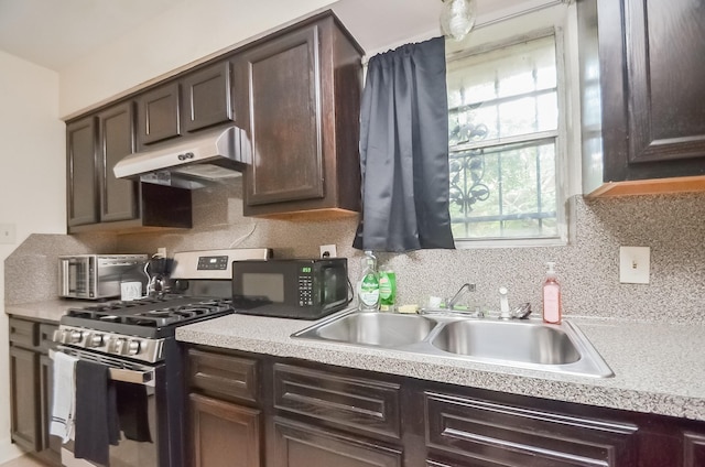 12806 Bauman Rd, North Houston, TX 77037 - kitchen featuring under cabinet range hood, gas stove, black microwave, and dark brown cabinetry