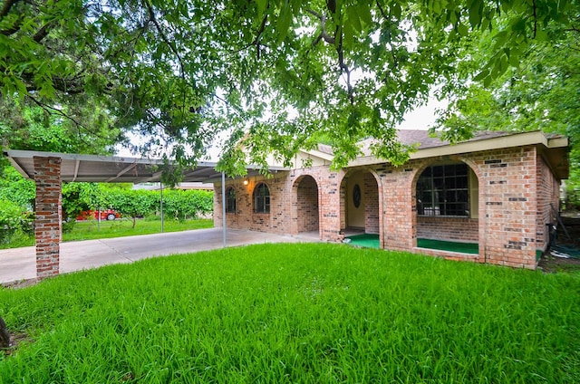 12806 Bauman Rd, North Houston, TX 77037 - view of front of property featuring a front yard, a carport, brick siding, and concrete driveway