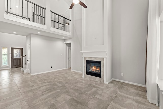 3506 Lake Bella Megan Dr, Katy, TX 77493 - unfurnished living room featuring a ceiling fan, a fireplace, a towering ceiling, stairs, and recessed lighting