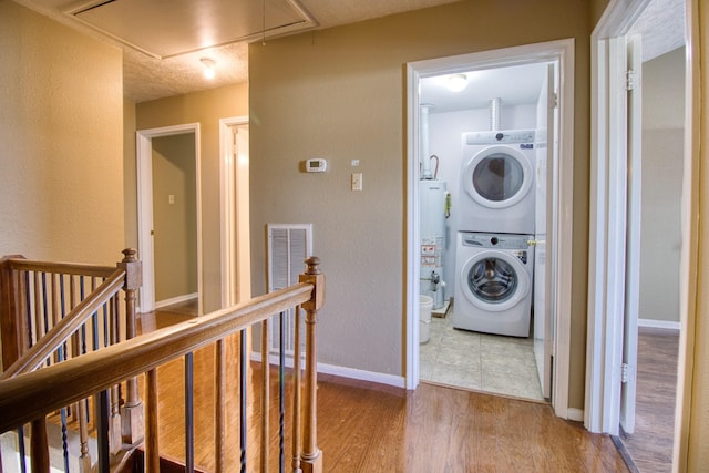 11667 Sabo Rd, Houston, TX 77089 - laundry area with attic access, stacked washer and clothes dryer, water heater, and wood finished floors