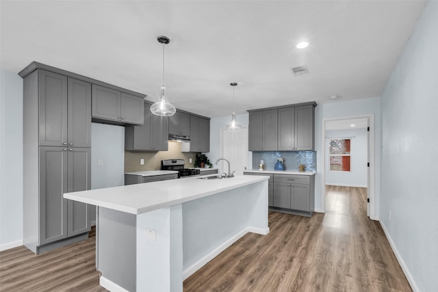 8215 Canyon St, Houston, TX 77051 - kitchen with stainless steel range with gas cooktop, gray cabinetry, decorative backsplash, wood finished floors, and light countertops