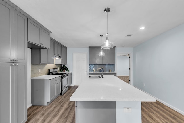 8215 Canyon St, Houston, TX 77051 - kitchen featuring stainless steel gas range, gray cabinets, backsplash, wood finished floors, and an island with sink