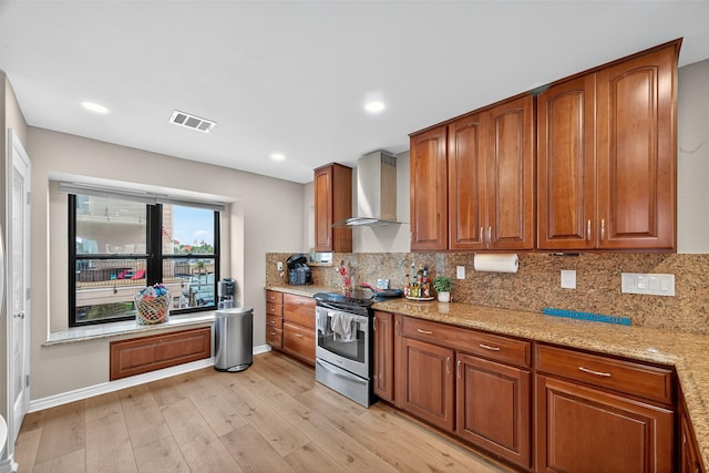 3663 Nasa Pkwy Unit 301, Seabrook, TX 77586 - kitchen with stainless steel range with electric stovetop, wall chimney range hood, brown cabinets, light wood-type flooring, and backsplash