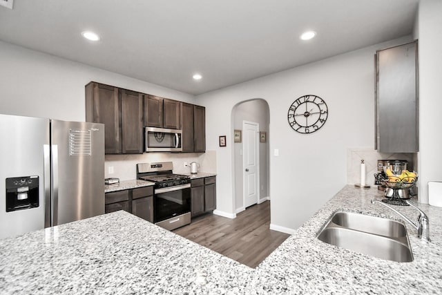 2832 Madison Dr, Conroe, TX 77304 - kitchen featuring appliances with stainless steel finishes, arched walkways, dark brown cabinets, dark wood-style flooring, and recessed lighting