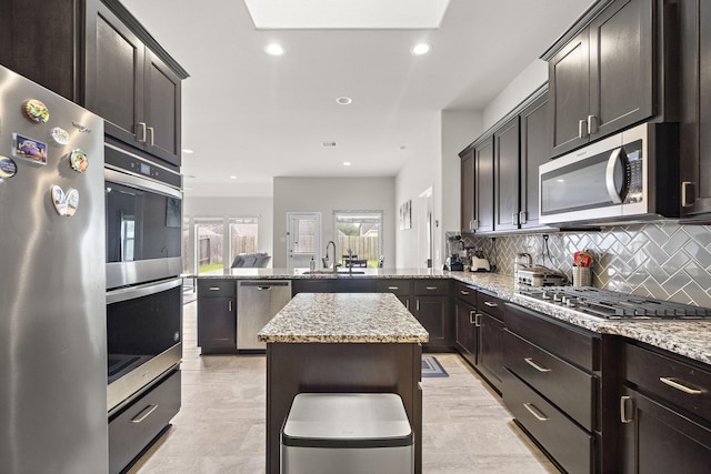 5442 Atwood Canyon Ct, Richmond, TX 77407 - kitchen featuring stainless steel appliances, a peninsula, light stone counters, decorative backsplash, and recessed lighting