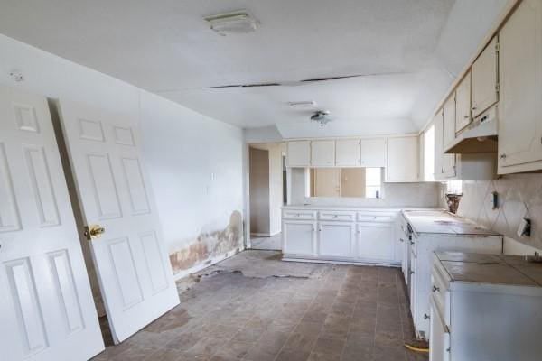 7973 Ritz St, Houston, TX 77028 - kitchen with under cabinet range hood, white cabinets, and light countertops