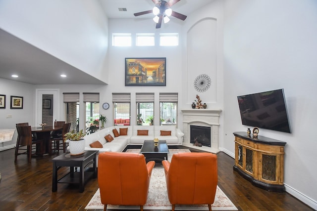 2710 Indigo Manor Ln, Katy, TX 77494 - living room with a towering ceiling, dark wood-style flooring, a ceiling fan, plenty of natural light, and a fireplace with raised hearth