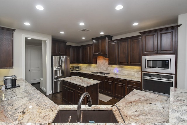 2710 Indigo Manor Ln, Katy, TX 77494 - kitchen with stainless steel appliances, light stone countertops, dark brown cabinets, recessed lighting, and backsplash