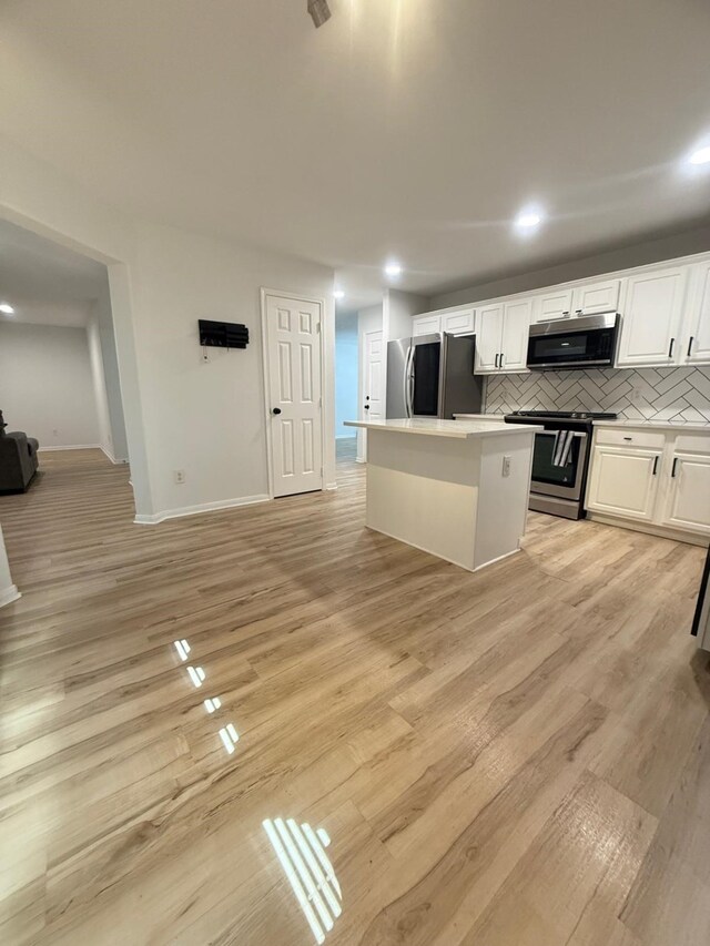 20918 Southhook Ct, Houston, TX 77073 - kitchen featuring appliances with stainless steel finishes, a center island, white cabinetry, backsplash, and light wood finished floors