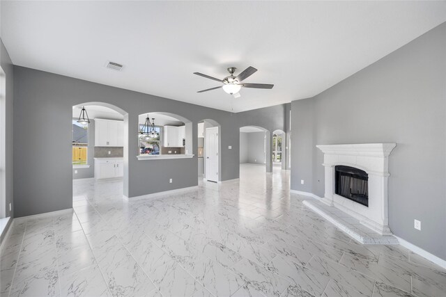537 Green Cedar Dr, League City, TX 77573 - unfurnished living room with a ceiling fan, a fireplace with raised hearth, arched walkways, and light marble finish floors