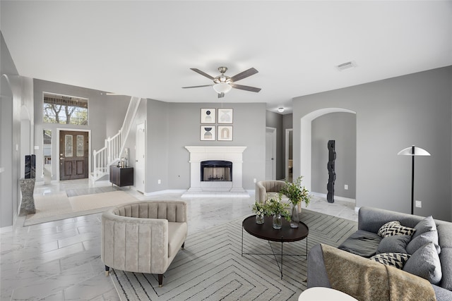 537 Green Cedar Dr, League City, TX 77573 - living area featuring light marble finish floors, a fireplace with raised hearth, stairs, a ceiling fan, and arched walkways
